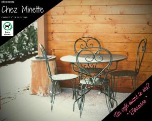 een tafel en stoelen voor een houten muur bij Le "Chalet de Minette" 2 étoiles La Bresse in La Bresse