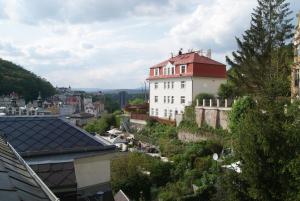 un bâtiment blanc avec un toit rouge sur une colline dans l'établissement Karlovy Vary, Dům u Máří Magdalény - 100 m od Vřídla, à Karlovy Vary