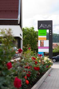 un panneau devant un hôtel avec des fleurs dans l'établissement Altus Hotel & Spa, à Praid