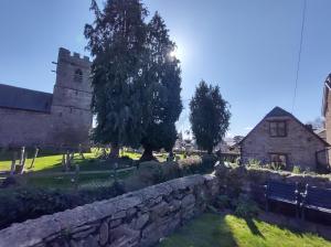 un ancien bâtiment en pierre avec un arbre et un mur en pierre dans l'établissement Penybont Barn, à Llangorse