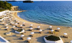 une plage de sable avec des parasols et l'océan dans l'établissement RENATA Mare HOLLIDAY HOUSE, à Rovinj