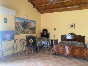 1 dormitorio con 1 cama, TV y sillas en Azienda agricola La Torre, en Corleone