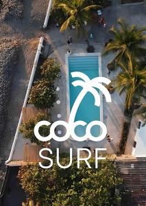 ein Schild an der Seite eines Gebäudes mit einer Palme in der Unterkunft Coco Surf Tropical Village in La Libertad