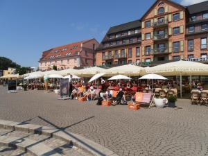 eine Gruppe von Menschen, die unter Sonnenschirmen auf einer Straße sitzen in der Unterkunft Großes, einzeln stehendes Ferienhaus "Undine", ruhige Lage, Terrasse, Parkplatz, Fahrradhäuschen abschließbar, Nähe zur Altstadt und 600 m zum Müritz - Strand in Waren (Müritz)