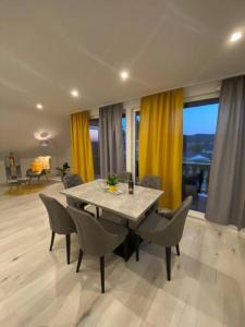 einen Esstisch und Stühle im Wohnzimmer mit gelben Vorhängen in der Unterkunft Ferienwohnung Eifel Stadtkyll in Stadtkyll
