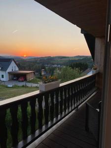 uma varanda com vista para o pôr-do-sol a partir de uma casa em Ferienwohnung Eifel Stadtkyll em Stadtkyll