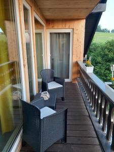un porche con sillas y mesas en el balcón en Ferienwohnung Eifel Stadtkyll, en Stadtkyll