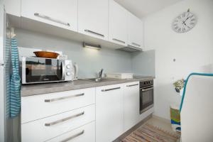 a white kitchen with a microwave and a sink at Frana Blue apartment in Split