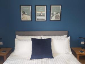 niebieska ściana z czterema zdjęciami nad łóżkiem w obiekcie Bay House w mieście Totland