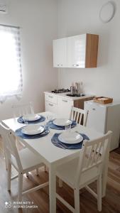 a kitchen with a white table with four chairs at IL GUFO DELLA MARZA in Ispica