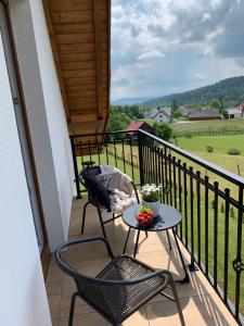 a balcony with a table and chairs and a view of a field at ORAWSKA CHATA pod Babią Górą in Zubrzyca Górna
