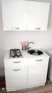 - une cuisine blanche avec évier et cuisinière dans l'établissement IL GUFO DELLA MARZA, à Ispica