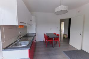 a kitchen with a sink and a table with red chairs at B&B DIVINO in Calceranica al Lago
