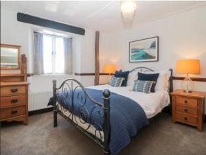 a bedroom with a bed and a dresser and a window at Tubs Cottage in Kingsteignton