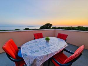 een tafel en stoelen op een balkon met uitzicht op de zonsondergang bij Vila Cicovac in Novalja