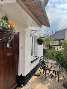 een patio met een tafel en stoelen voor een huis bij Tubs Cottage in Kingsteignton