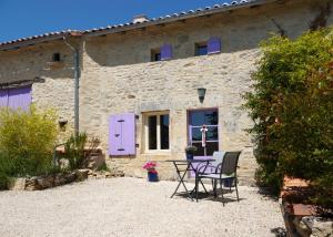 a stone house with a table and chairs in front of it at Gite Rural La Maison Mauve in Ventouse