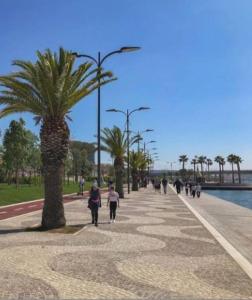 un groupe de personnes marchant sur un trottoir avec un palmier dans l'établissement OLdBIA, à Olbia