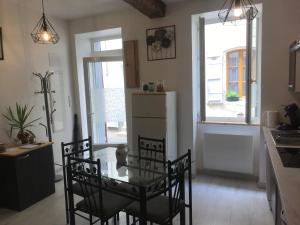 a kitchen with a glass table and chairs and a window at Maison chaleureuse au centre ville in Nérac