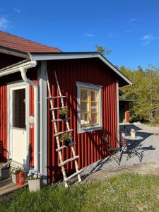 SparreholmLoves Bondgård的一座红色的房子,房子的一侧有梯子