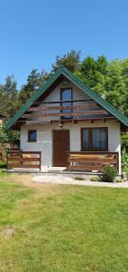 a house with two benches in front of it at Domki letniskowe "U Adaska" in Chałupy