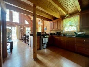 uma cozinha com armários de madeira e um forno com placa de fogão em Beddington Lake Log Cabin 