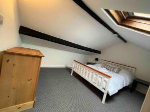 a bedroom with a white bed and a wooden dresser at Fisherman Cottage Morecambe in Morecambe