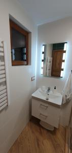 a white bathroom with a sink and a mirror at Domki letniskowe "U Adaska" in Chałupy