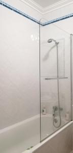 a glass shower door in a bathroom with a tub at Maré Alta by CS in Olhos de Água