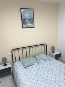 a bedroom with a bed with two night stands and a picture on the wall at Maison chaleureuse au centre ville in Nérac