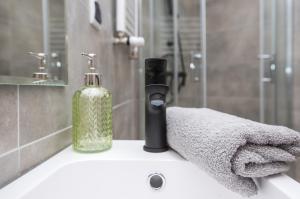 - un lavabo avec une bouteille de savon et des serviettes dans l'établissement Apartament Mikołowska 2, à Gliwice
