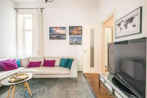 ein Wohnzimmer mit einem weißen Sofa und einem Flachbild-TV in der Unterkunft Großzügige Altbauwohnung in Bestlage in Hamburg