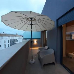 a white umbrella and a chair on a balcony at Cosy Appartement Au Centre de Casablanca in Casablanca