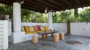 a porch with a bench and a table and some trees at Oliveyard Stone Built House- with pool non chlorin in Koskinou