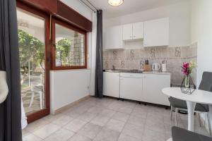 cocina con armarios blancos y mesa en Apartments Bozan, en Trogir
