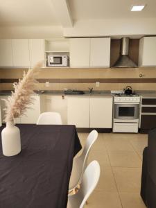 cocina con mesa negra y armarios blancos en Lujoso apartamento cómodo y luminoso con seguridad 24 hs y estacionamiento en Guaymallén