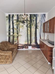 a kitchen with a couch and a mural of trees at Apartament Kosynka 