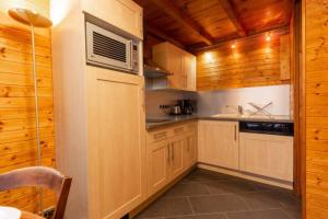 a kitchen with wooden cabinets and a microwave at Chalet individuel à proximité de la station Les 7 Laux in Les Adrets