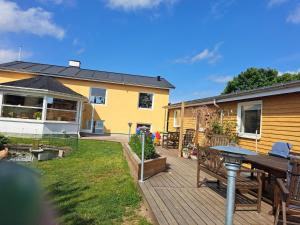 eine Holzterrasse mit einem Tisch und einem Haus in der Unterkunft Eltvedhus Feriebolig in Hjørring