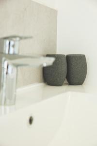 - une salle de bains avec 3 tasses grises sur un comptoir dans l'établissement Little Cocoon ~ T2 douillet, à Vierzon