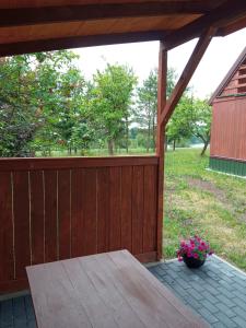 una terraza de madera con una mesa y flores. en Sielanka na wzgórzu, en Czostków