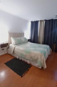 1 dormitorio con 1 cama con cortinas azules y alfombra en M-Montt Providencia Apartamentos Amoblados, en Santiago