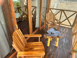 2 Holzstühle und ein Tisch auf der Veranda in der Unterkunft bacalar My Love Front Laguna in Bacalar