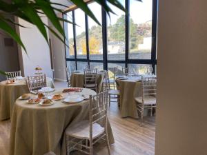 A PONTEVELLA Sobradelo, Alojamiento Boutique في Sobradelo: غرفة طعام بها طاولات وكراسي ونافذة كبيرة
