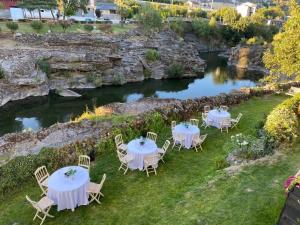 a group of tables and chairs on a lawn next to a river at A PONTEVELLA Sobradelo, Alojamiento Boutique in Sobradelo
