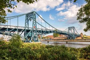 a blue bridge over a river with a city at Stilvolle Stadtoase, 116 qm, Parkblick, Wassernah, Parkplatz in Wilhelmshaven