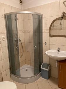 a shower with a glass door next to a sink at Apartament Turkus in Gdynia