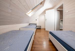 two beds in a room with wooden walls and wooden floors at Domki przy Mysliwskiej in Grzybowo