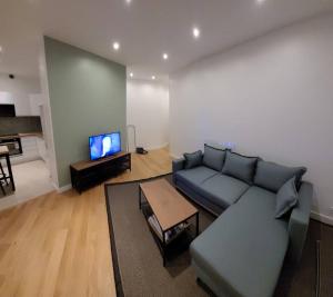 a living room with a couch and a tv at BLUMENTHAL in Épinay-sur-Seine