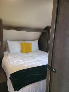 a bed with a yellow pillow on top of it at Beach and Bay Glamping in Bolivar Peninsula
